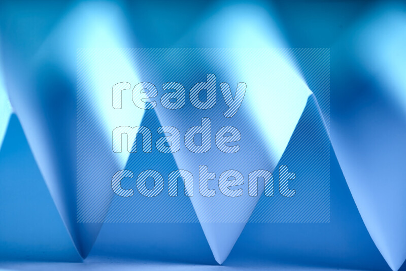 A close-up abstract image showing sharp geometric paper folds in blue gradients