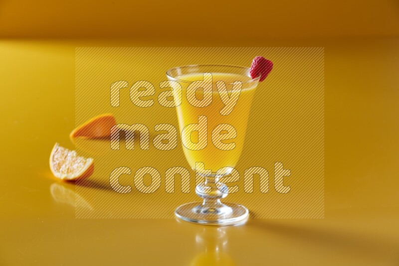 glass of orange juice with berry on yellow background