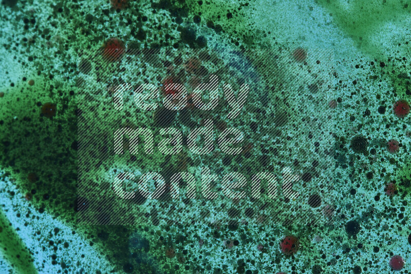 Close-ups of abstract red and green watercolor drops on oil Surface on green background