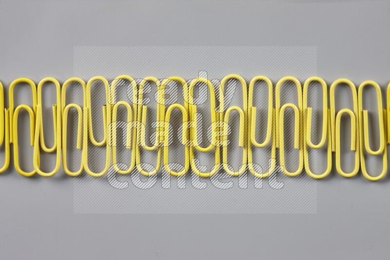 Yellow paper clips isolated on a grey background