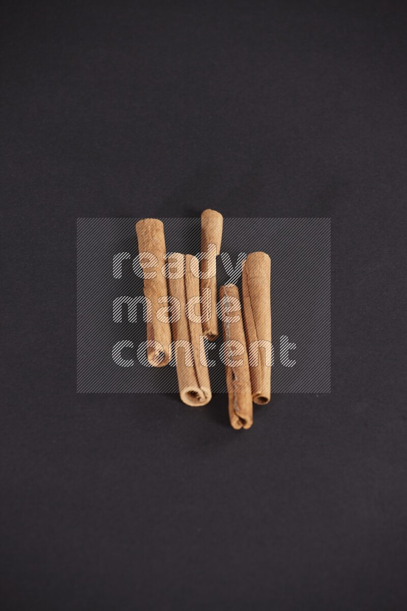 Cinnamon sticks stacked on black flooring