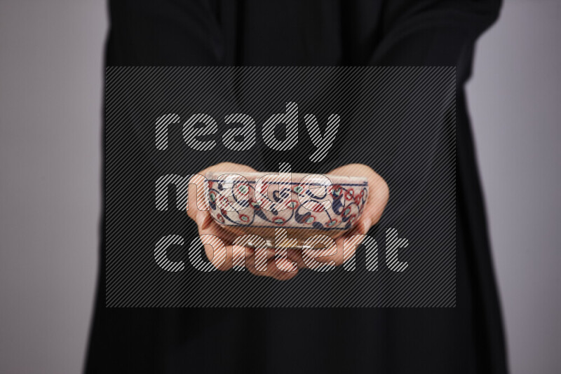 A woman in black abaya holding different pottery essentials in different positions