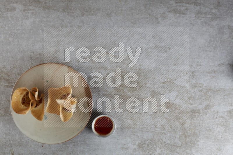 wonton cups with soy sauce ramkin on multi colored pottery on grey textured counter top