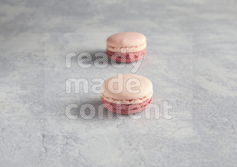45º Shot of two Pink Litchi Raspberry macarons  on white  marble background