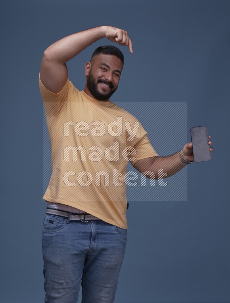 A man Showing His Smart Phone on Blue Background wearing Orange T-shirt