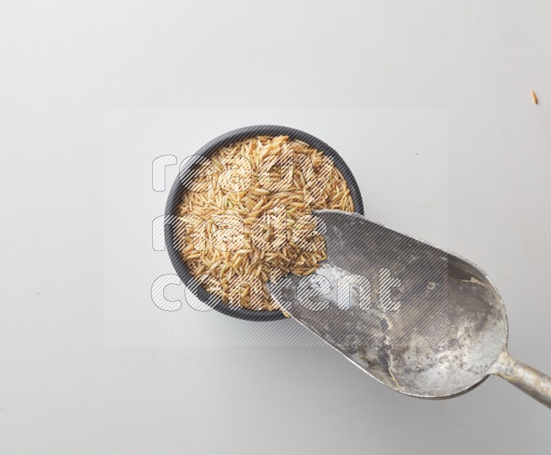 Top-view shot of long grain brown rice in a container on white background