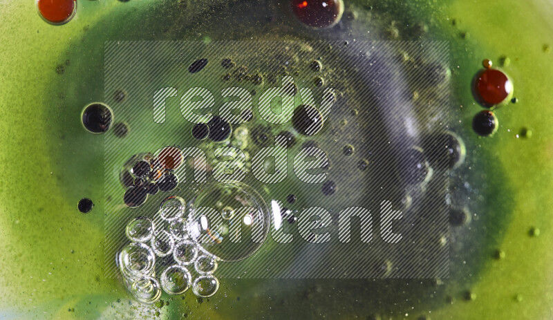 Close-ups of abstract red, green and blue watercolor drops on oil Surface on green background