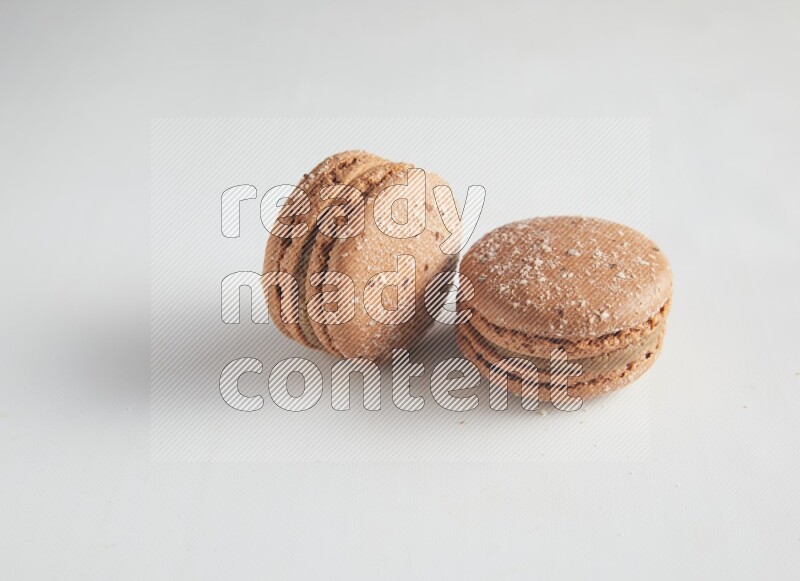 45º Shot of two Brown Hazelnuts macarons on white background