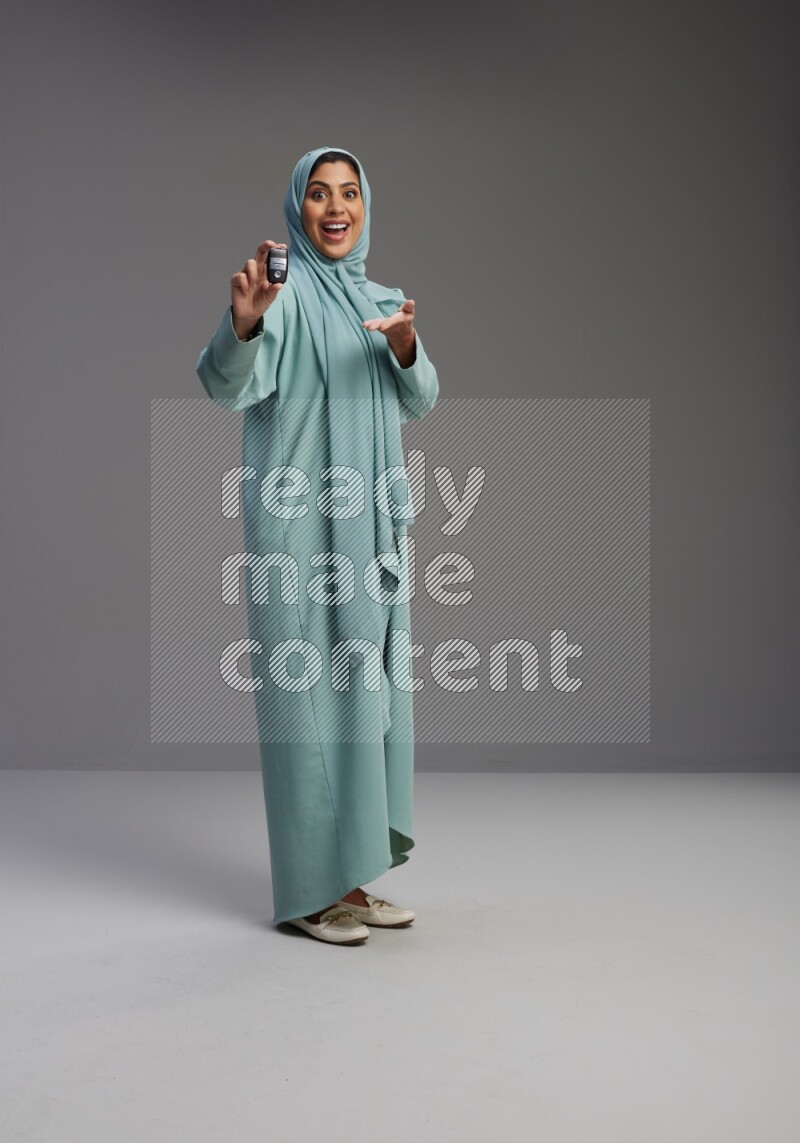 Saudi Woman wearing Abaya standing holding car key on Gray background