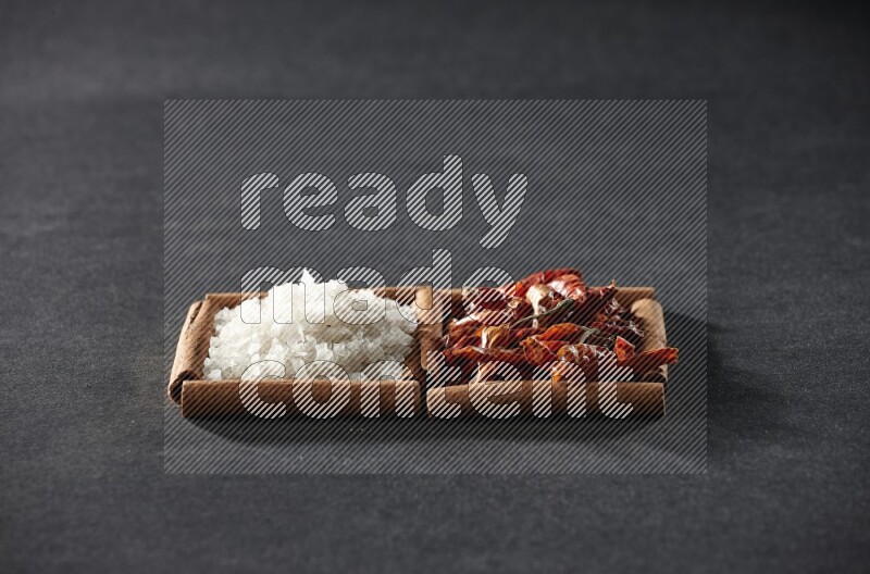 مربعان من أعواد القرفة ممتلئان بالفلفل الحار المجفف والملح الأبيض علي خلفية سوداء