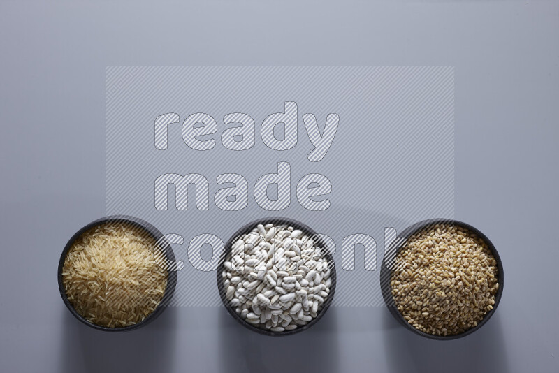Legumes in pottery bowls on light grey background