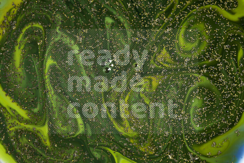 A close-up of sparkling gold glitter scattered on swirling green background