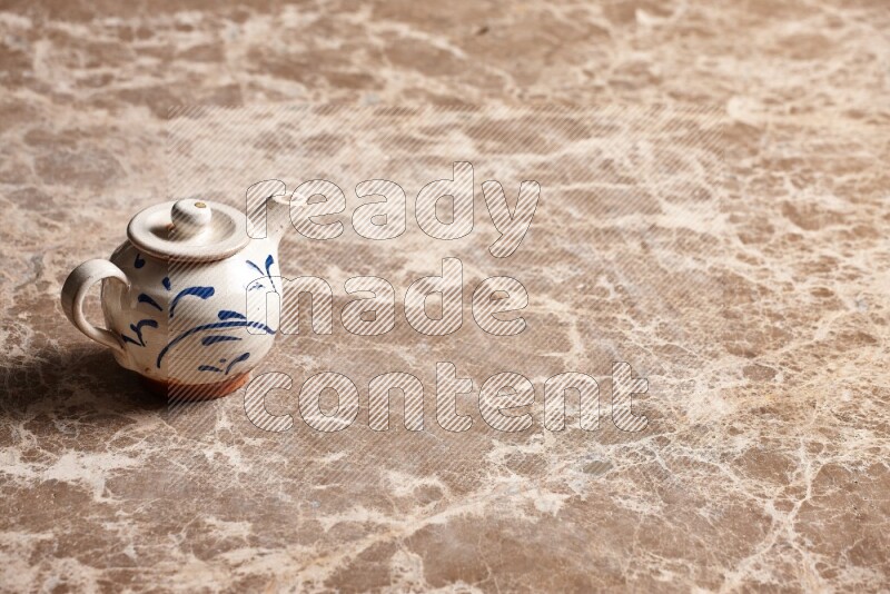 A pottery teapot on beige marble background