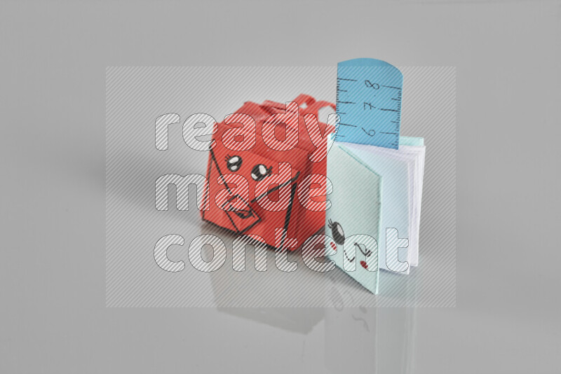 Origami school supplies such as back bag, books and ruler on grey background