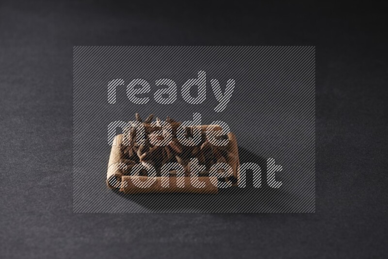 أربعة من أعواد القرفة مكونة شكل مربع بداخلها يانسون نجمي علي خلفية سوداء