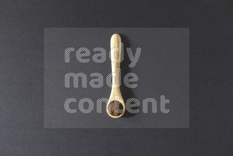 بودرة القرنفل في ملعقة خشبية علي خلفية سوداء