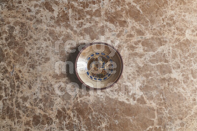 A decorative pottery plate on beige marble background