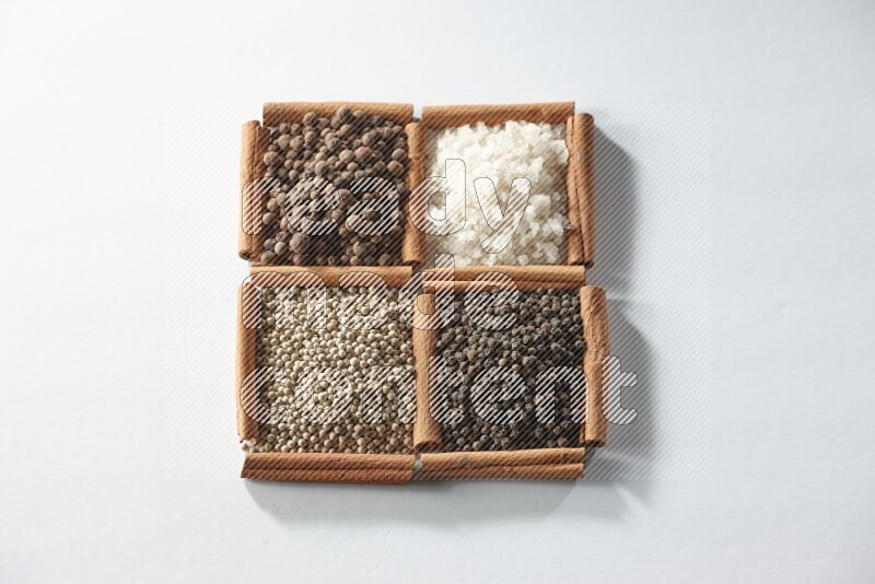 4 squares of cinnamon sticks full of allspice, white salt, white pepper and black pepper on white flooring