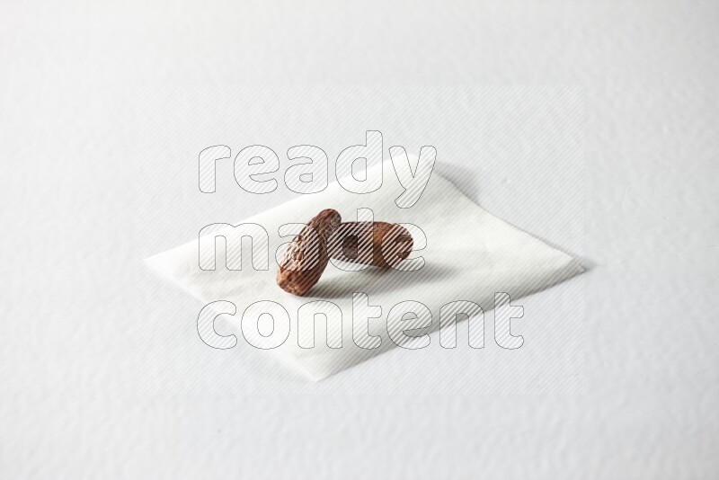 Two dried dates on a piece of paper on a white background in different angles