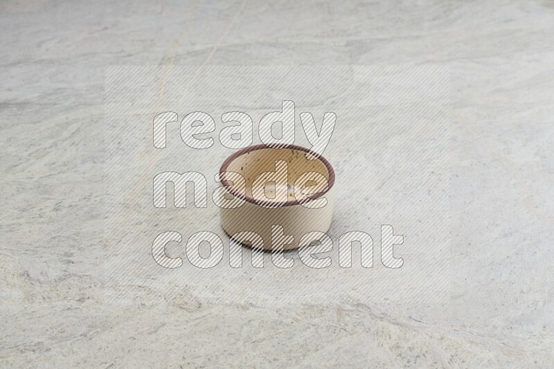 A beige pottery oven bowl on grey marble background