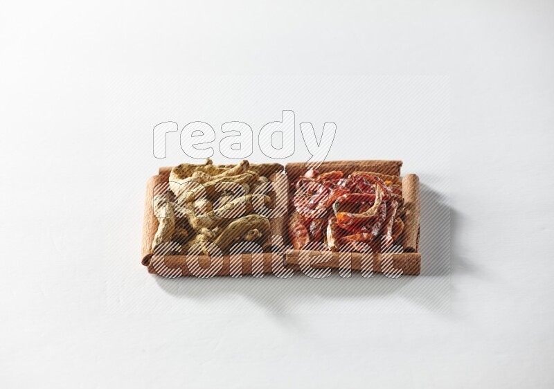 2 squares of cinnamon sticks full of dried red chilis and turmeric fingers on white flooring