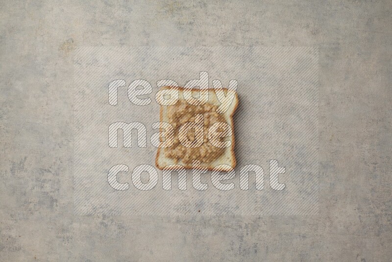 Crunchy peanut butter on a toasted white toast slices on a light blue textured background