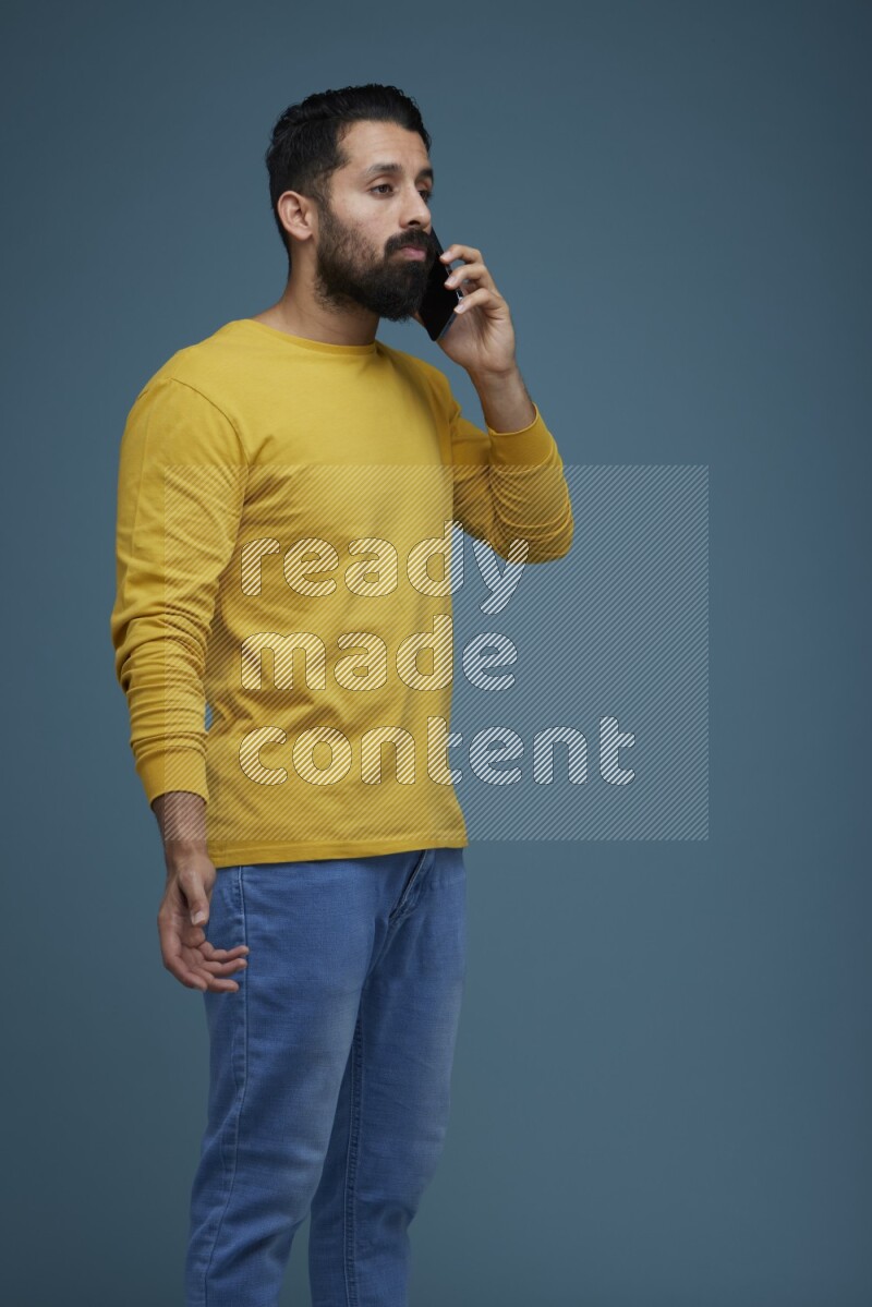 A man having a calling in a blue background wearing a yellow shirt