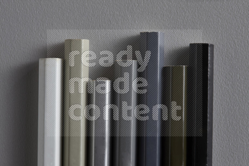 مجموعة من أقلام الرصاص الملونة مرتبة لتعرض تدرجا من اللون الأبيض والرمادي والأسود علي خلفية رمادية