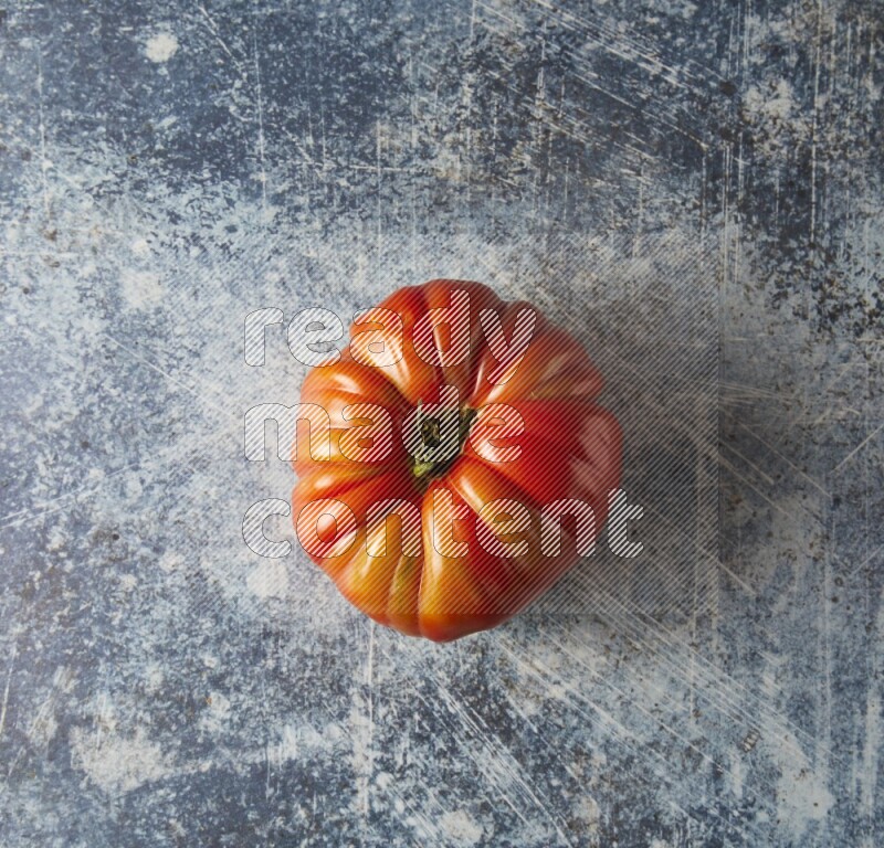 Single Topview Heirloom Tomato on a textured rustic blue background