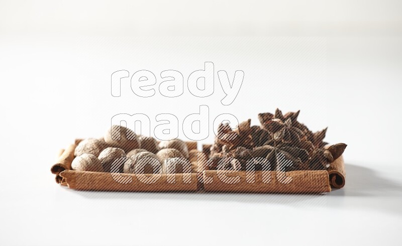 مربعان من أعواد القرفة ممتلئان باليانسون النجمي وجوزة الطيب علي خلفية بيضاء