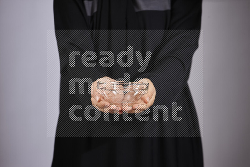 امرأة ترتدي عباءة سوداء تحمل أدوات زجاجية مختلفة في أوضاع متعددة