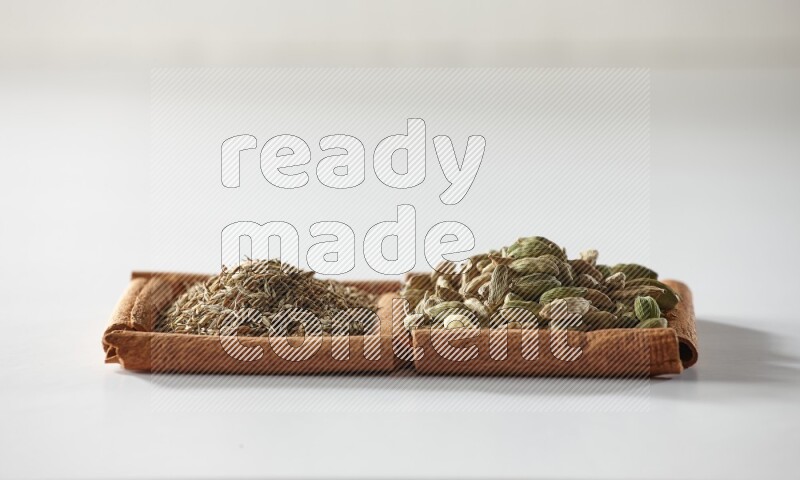 2 squares of cinnamon sticks full of cardamom and cumin on white flooring