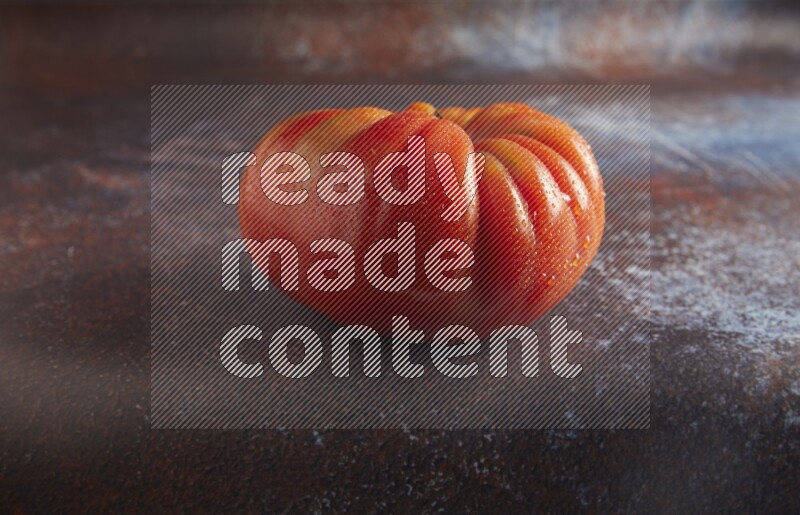 45 degree single heirloom tomato on  a textured reddish rustic metal background