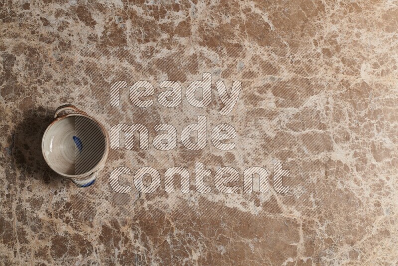 A multicolored pottery bowl on beige marble background