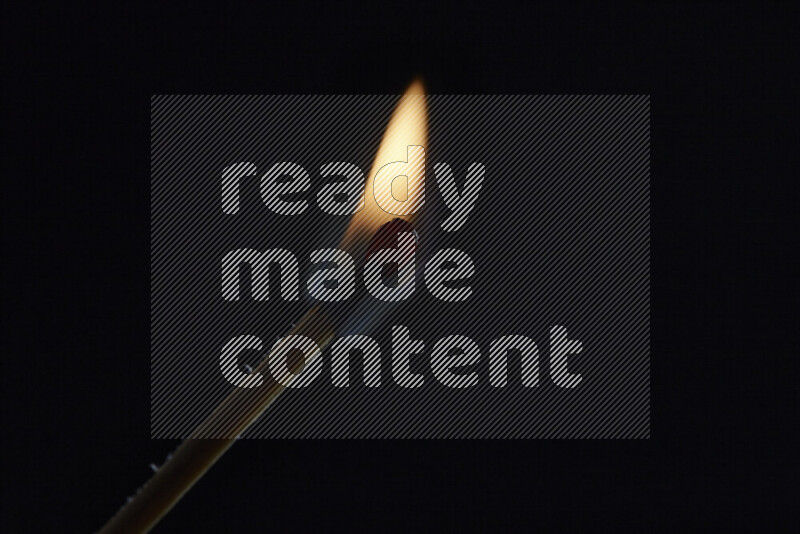A burning matchstick isolated on dark backdrop