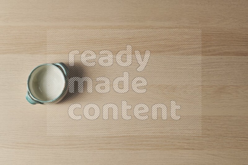 A multicolored pottery bowl on light wooden background