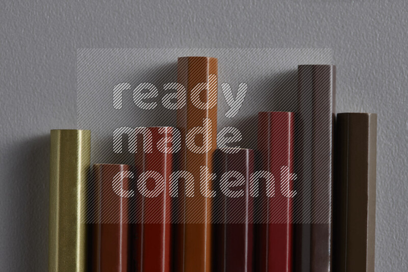 A collection of colored pencils arranged showcasing a gradient of brown hues on grey background