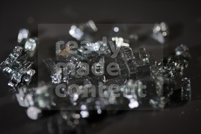 Transparent black fragments of glass scattered on a black background