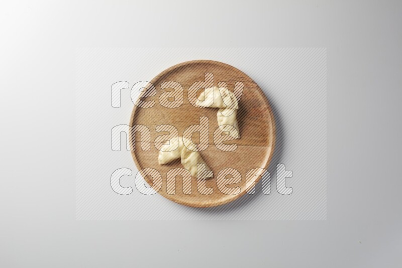 Four Sambosas on a wooden round plate on a white background
