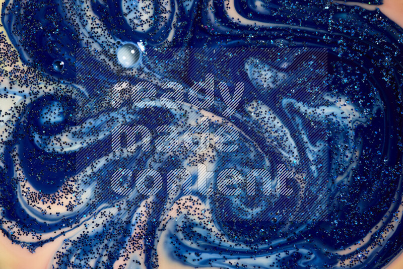 A close-up of sparkling blue glitter scattered on swirling blue and orange background