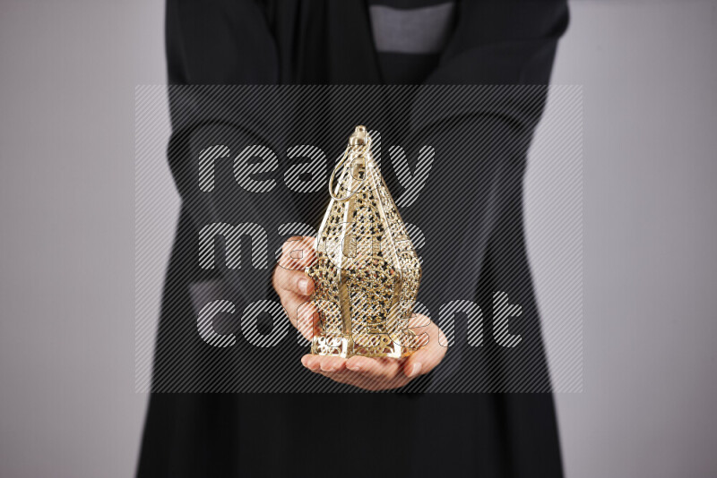 A woman in black abaya holding different ramadan lanterns in different positions