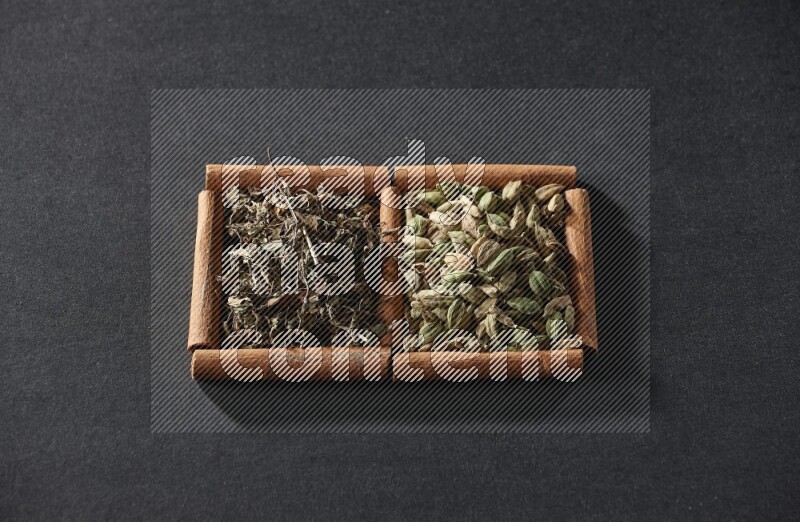 2 squares of cinnamon sticks full of cardamom and dried basil on black flooring