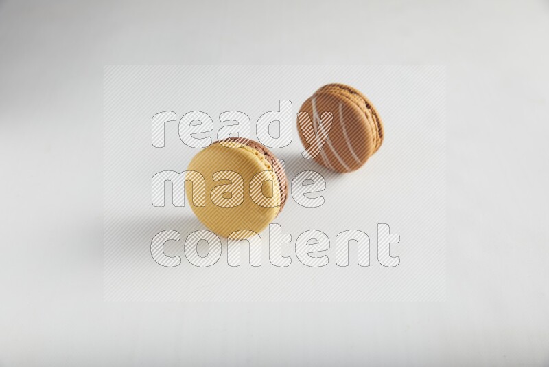 45º Shot of of two assorted Brown Irish Cream, and Yellow, and Brown Chai Latte macarons on white background