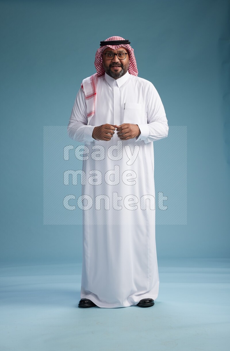 Saudi Man with shimag Standing Interacting with the camera on blue background