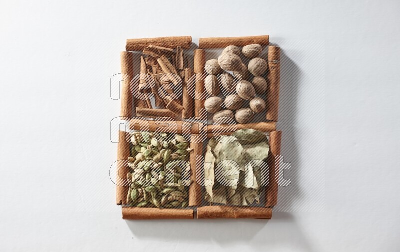 4 squares of cinnamon sticks full of nutmegs, bay laurel leaves, cardamom and cinnamon on white flooring