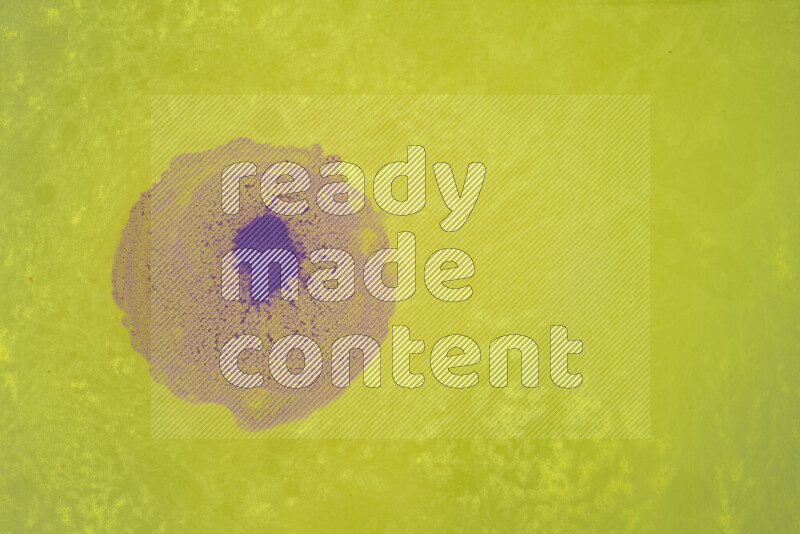 The image captures a dramatic splatter of purple paint over a yellow backdrop