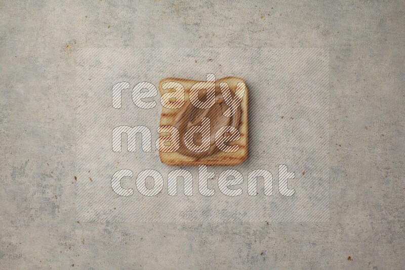 Creamy peanut butter on a toasted white toast slices on a light blue textured background