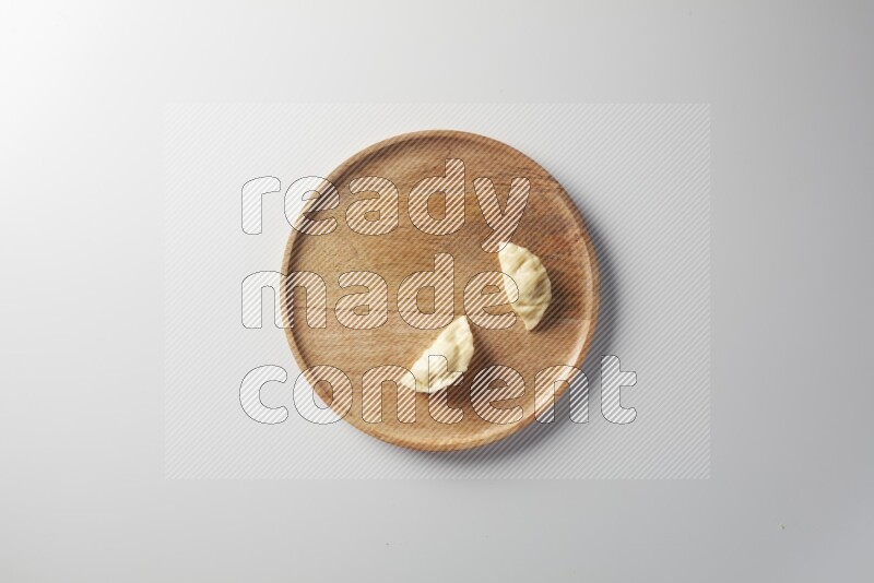 Two Sambosas on a wooden round plate on a white background