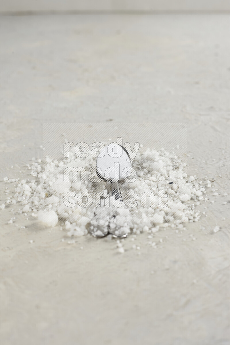 ملعقتان معدنيتان ممتلئتان بملح الطعام الناعم وملح الهايمالايا الناعم على خلفية بيضاء