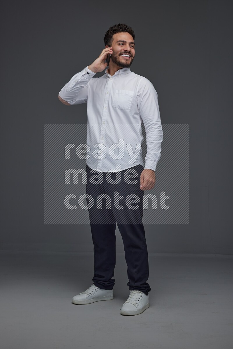 A man wearing smart casual talking in the phone eye level on a gray background